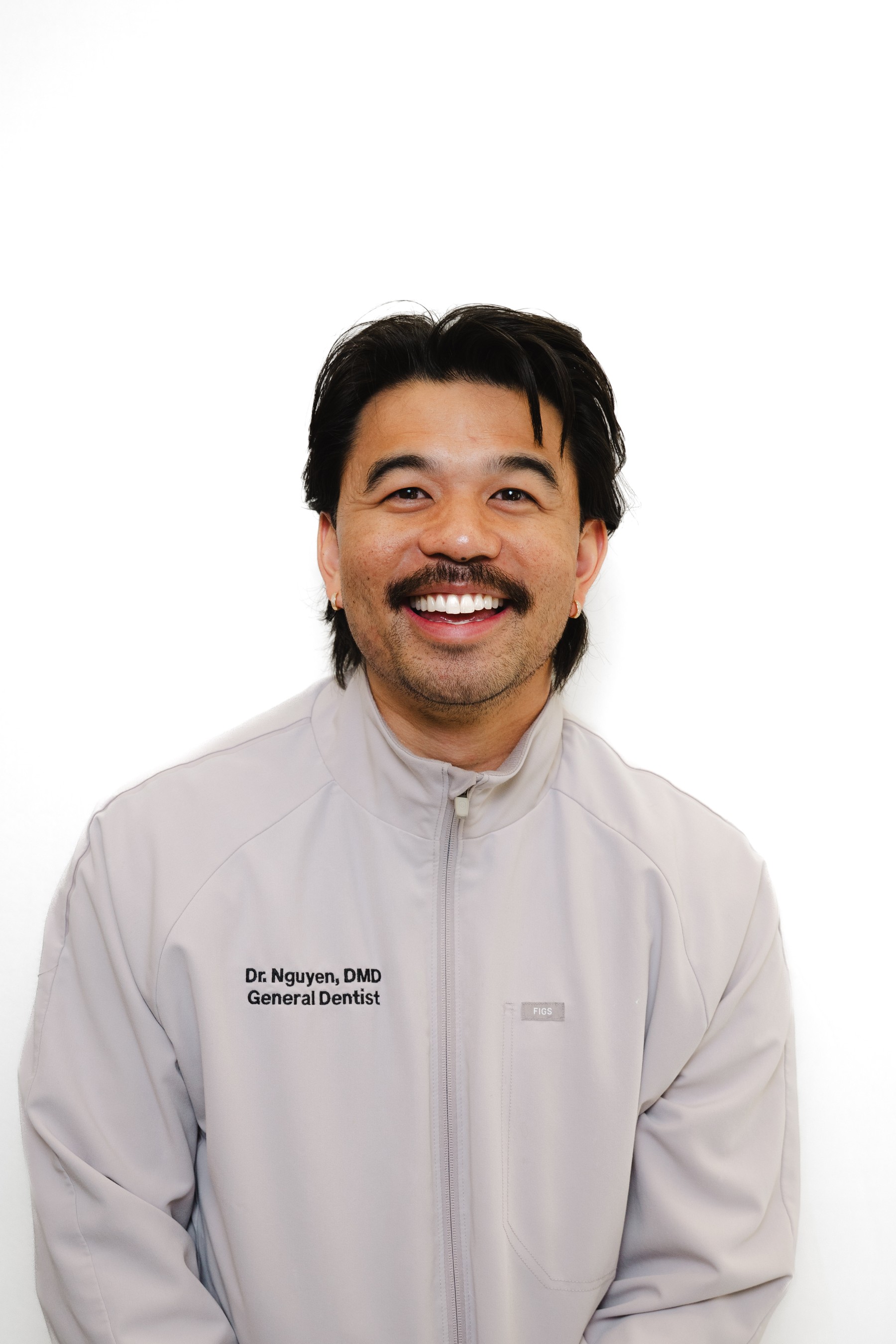 Dr. Khoa Nguyen, DMD, smiling in a white dental jacket