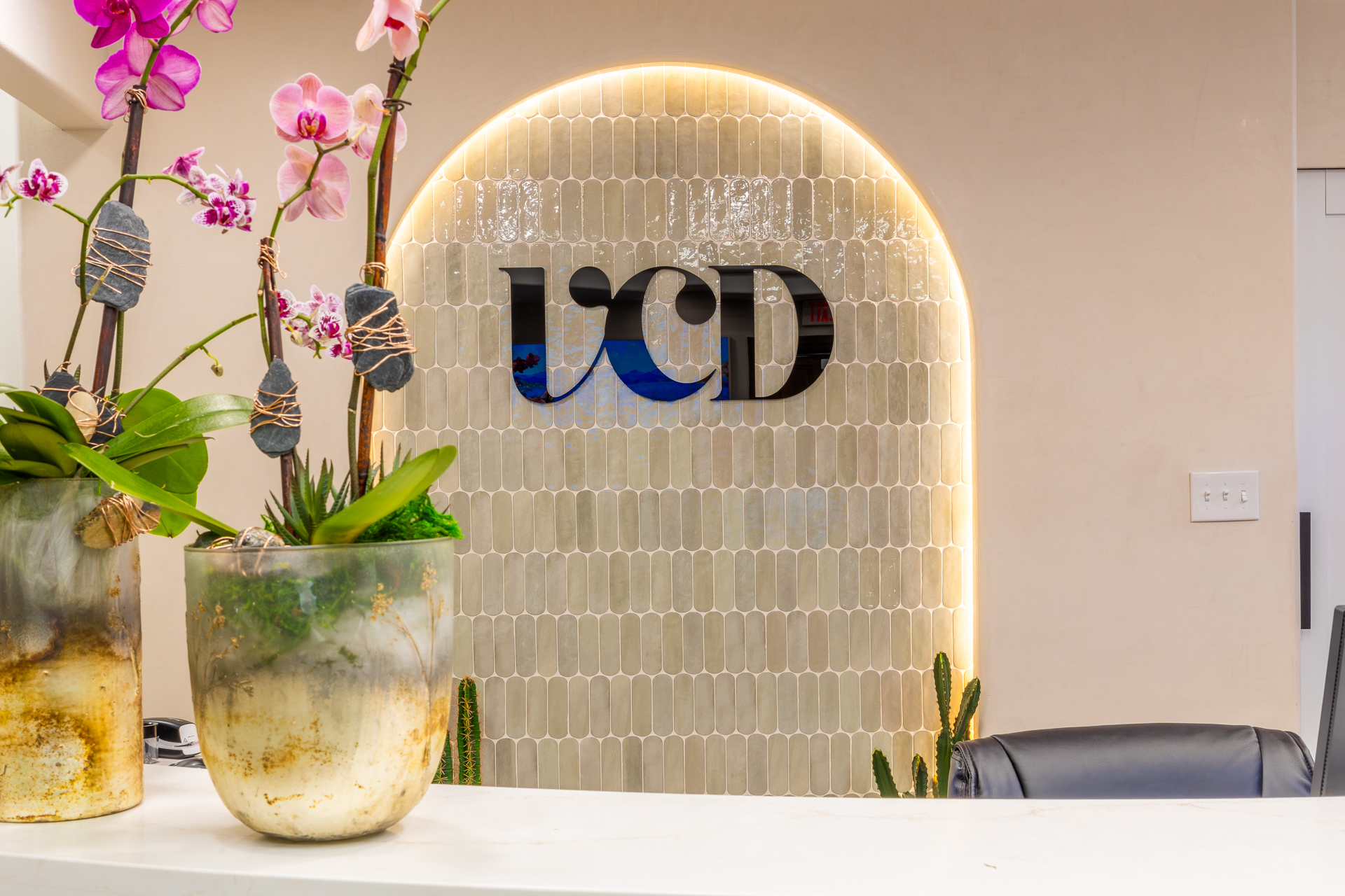Vegas Choice Dental reception desk with orchids and illuminated VCD logo